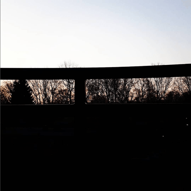 Een silhouet van een brug met bomen op de achtergrond