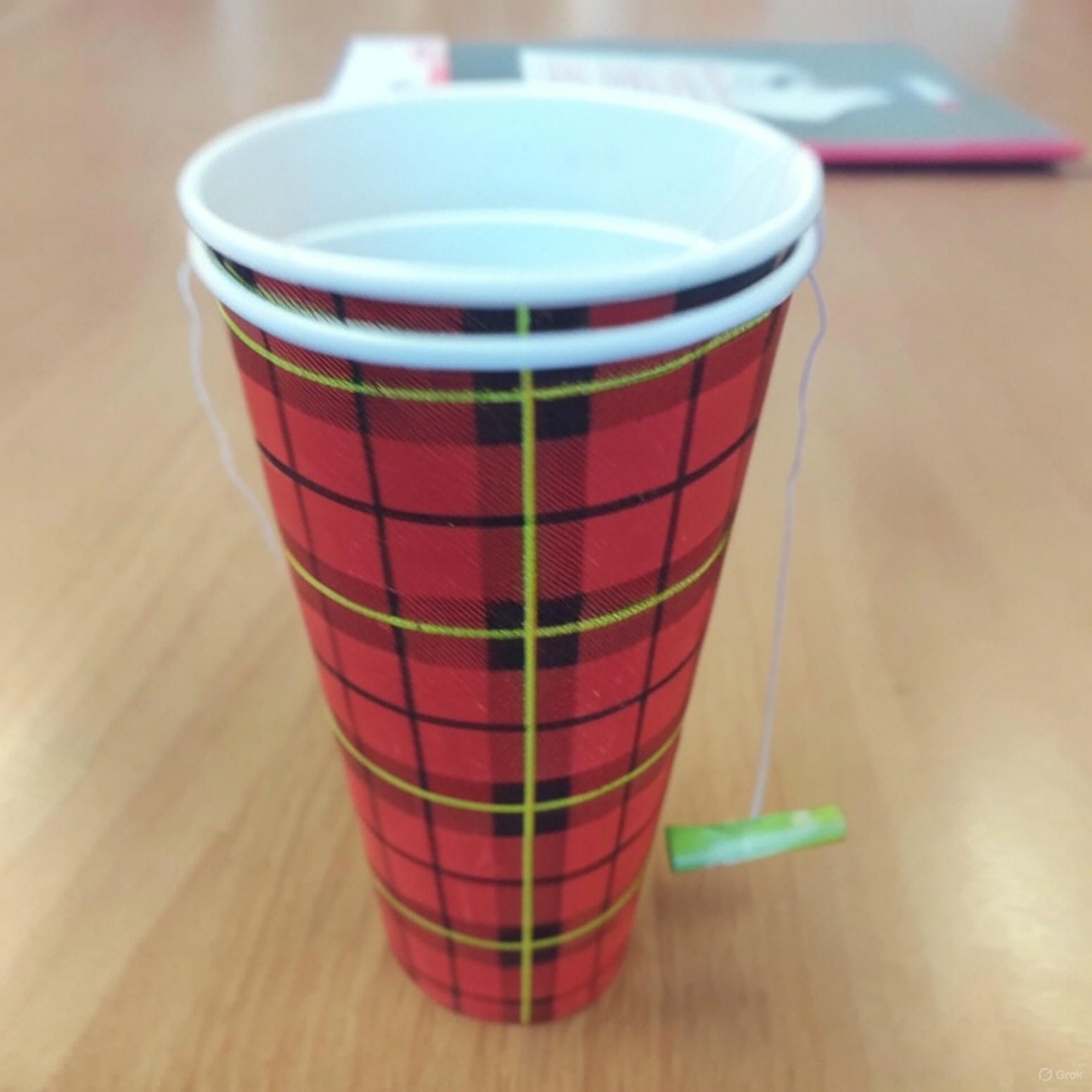 Een rood-witte kop met een ruitpatroon staat op een houten tafel