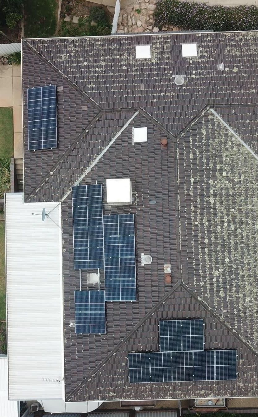 A Person Wearing Yellow Gloves Is Working on A Solar Panel — Brent Hawe Solar & Electrical in Glenfield Park, NSW