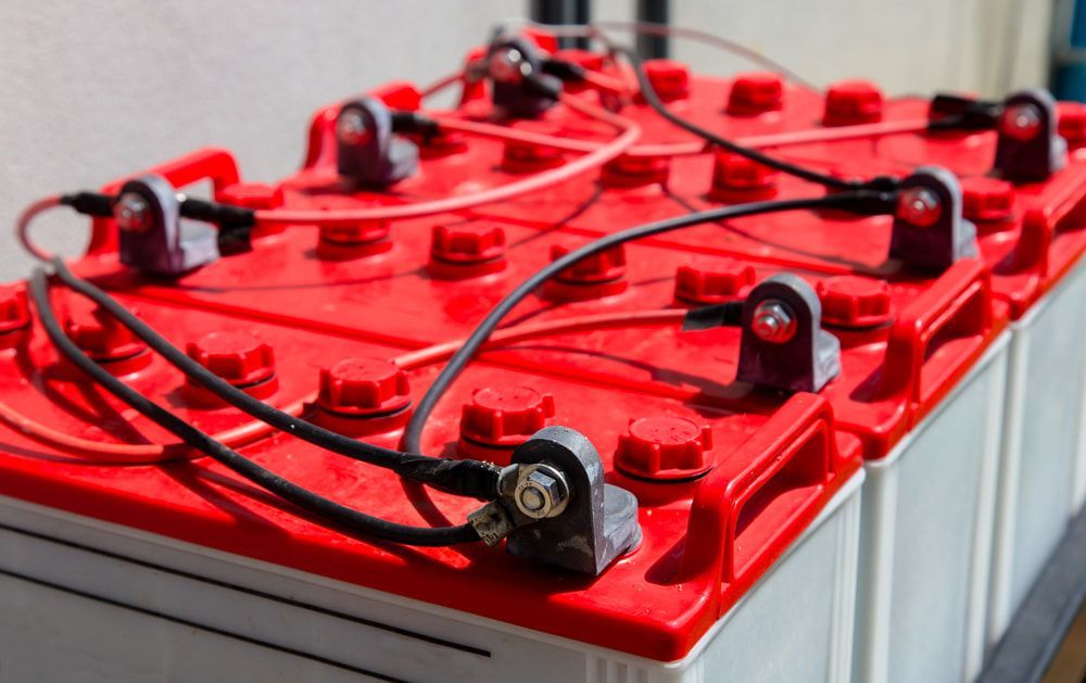 A Bunch of Red Batteries Are Sitting on Top of Each Other on A Table — Brent Hawe Solar & Electrical in Glenfield Park, NSW