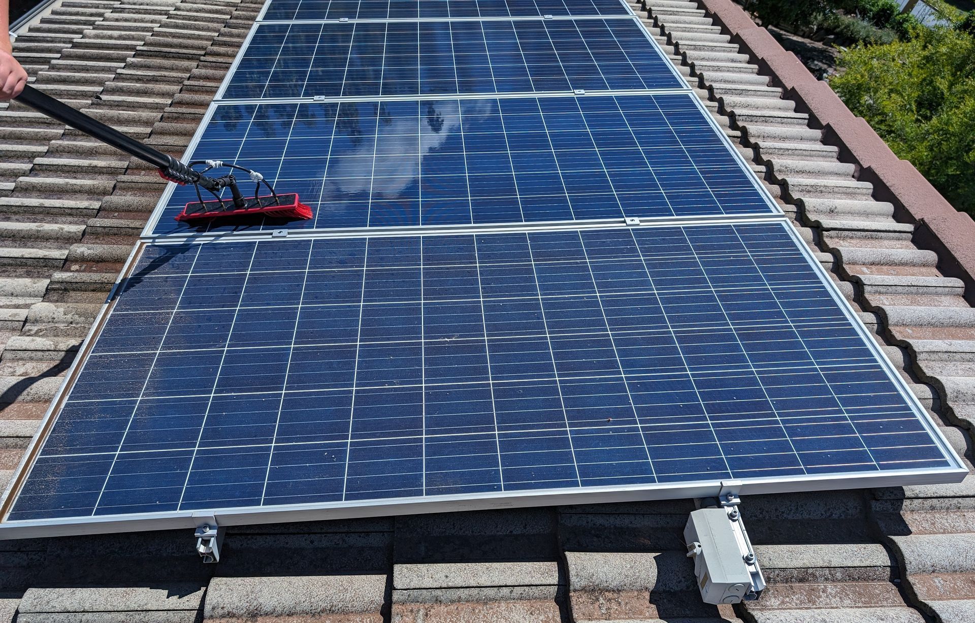 A Man Is Installing Solar Panels on The Roof of A Building — Brent Hawe Solar & Electrical in Glenfield Park, NSW