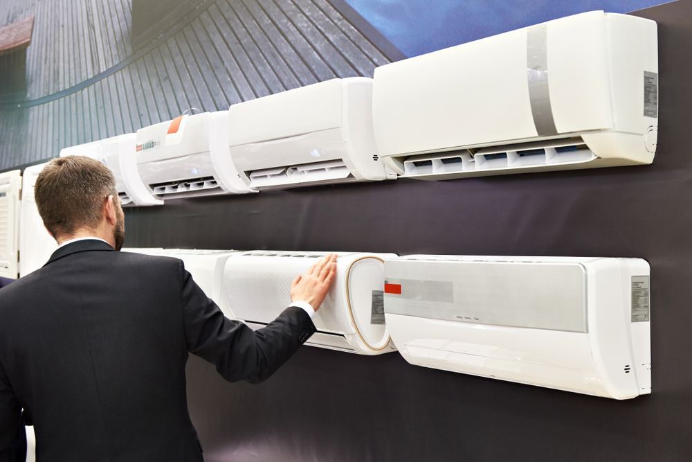 Man in Suit Examining a Row of White Ductless Mini-Split Air Conditioners — Coolman Airconditioning in Broken Head, NSW