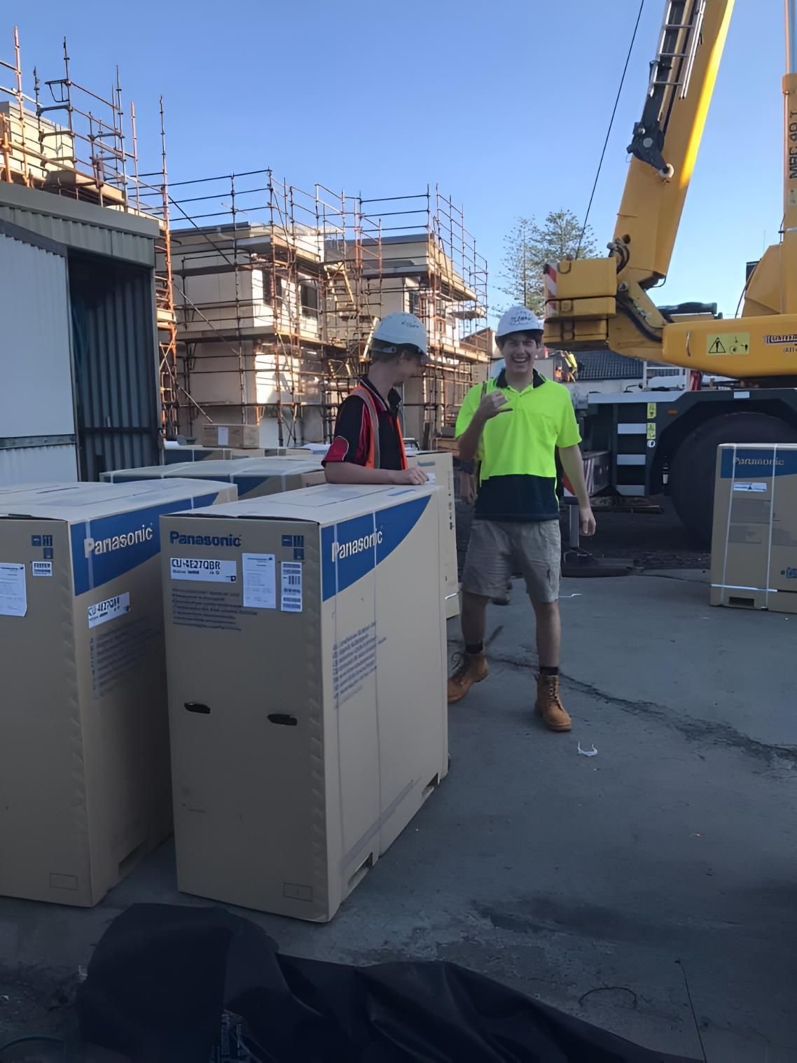 Two Men Are Standing Next to a Large Box — Coolman Airconditioning in Brunswick Heads, NSW