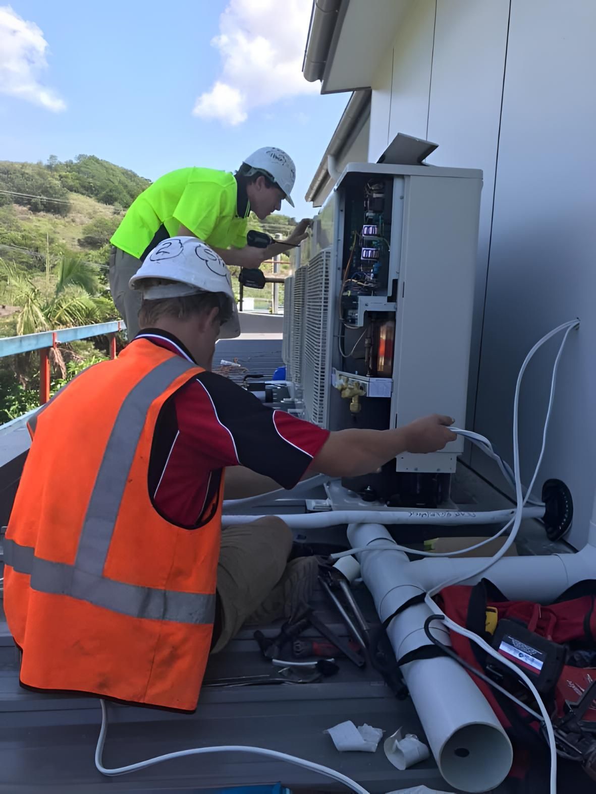 Two Men Are Working on an Air Conditioner — Coolman Airconditioning in Wollongbar, NSW