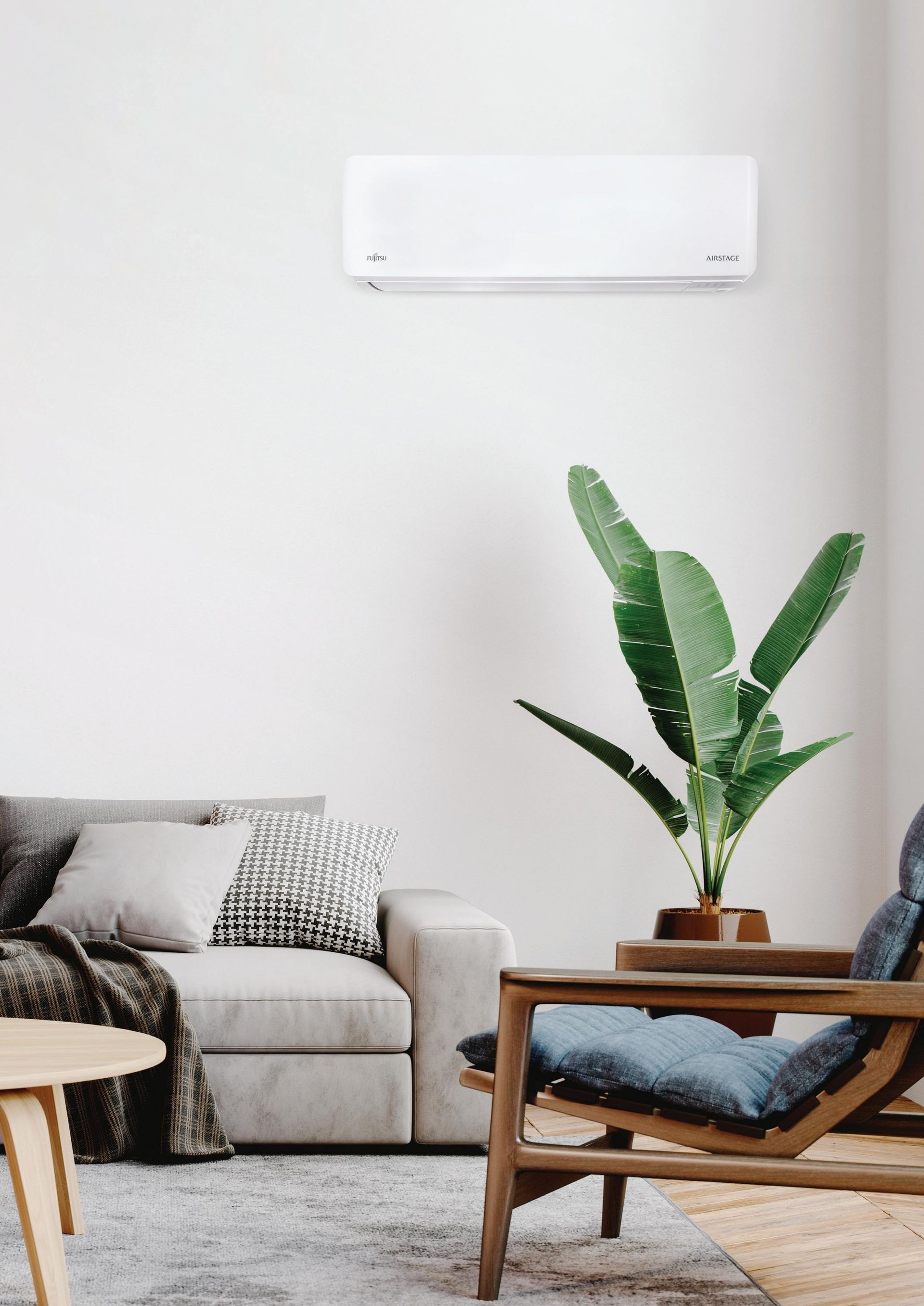 Modern living room with air conditioner, sofa, chair, and a plant— Coolman Airconditioning in Broken Head, NSW