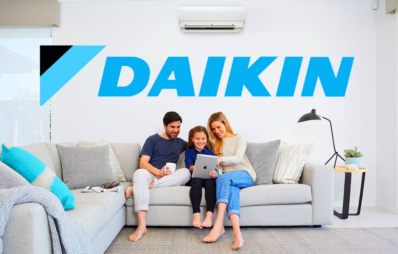 Dakin Air Conditioning with a family sitting in the lounge and a air con unit in the back ground  — Coolman Airconditioning in Broken Head, NSW
