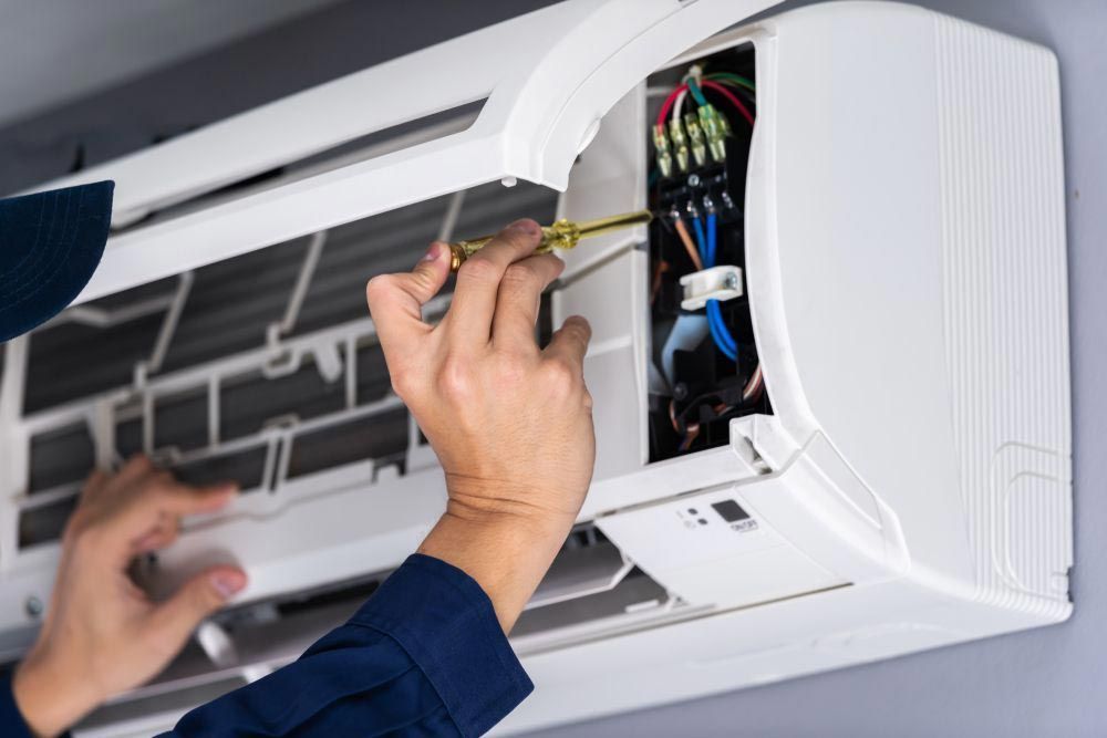 Person is Fixing an Air Conditioner With a Screwdriver — Coolman Airconditioning in Broken Head, NSW