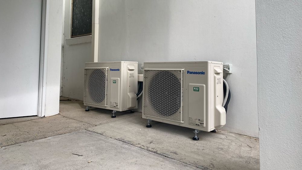 Two Air Conditioners Are Sitting Next to Each Other — Coolman Airconditioning in Broken Head, NSW