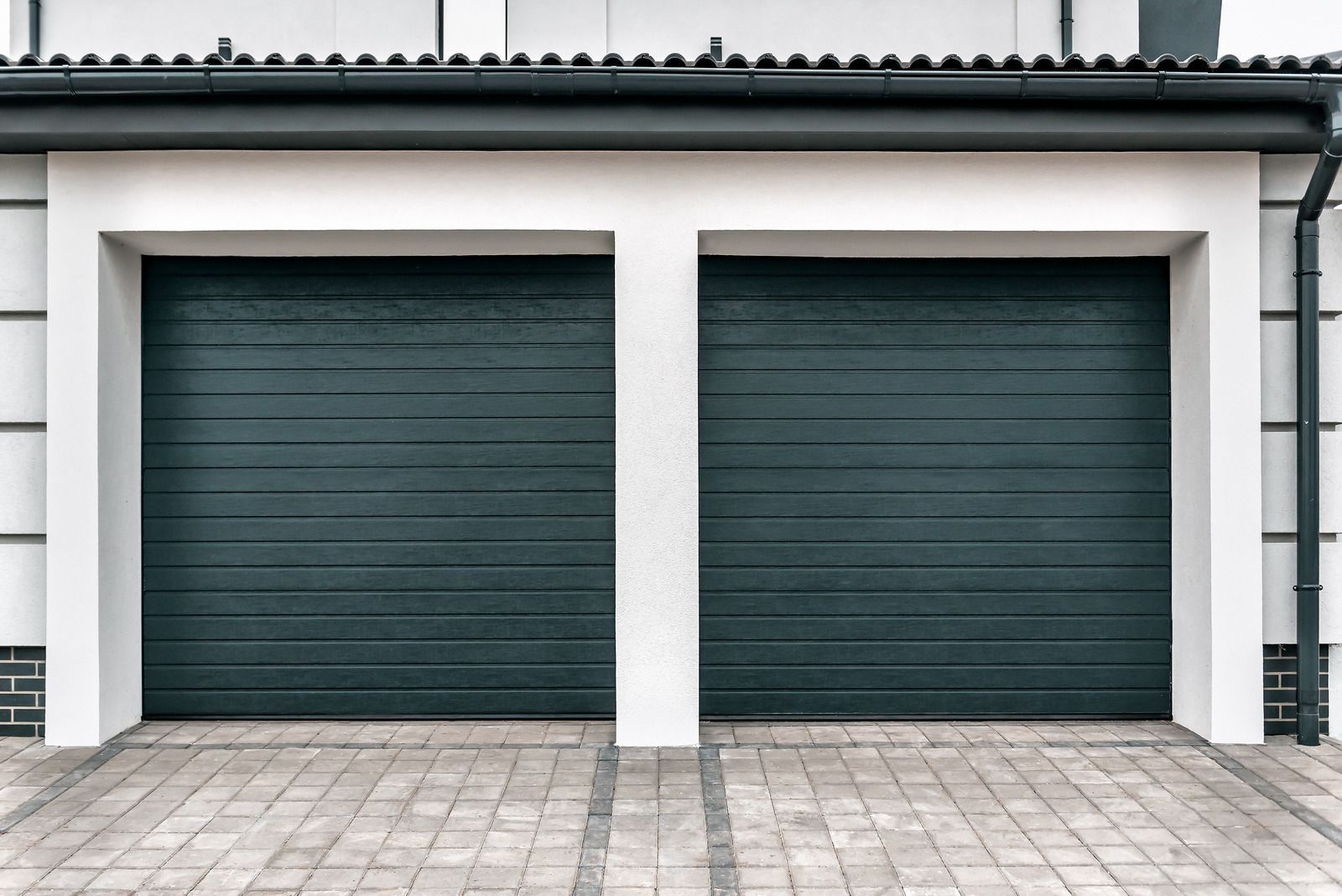 There are two garage doors on the side of a house.