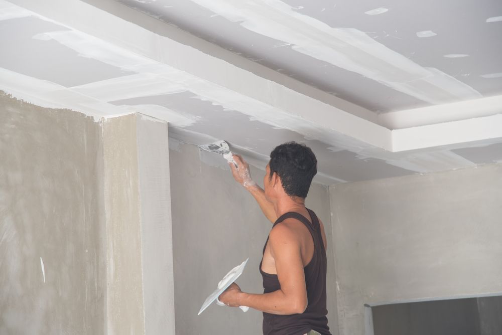 Man Applying Drywall Mud to A Ceiling with A Trowel — Completely Plastered North Coast in Alstonville, NSW