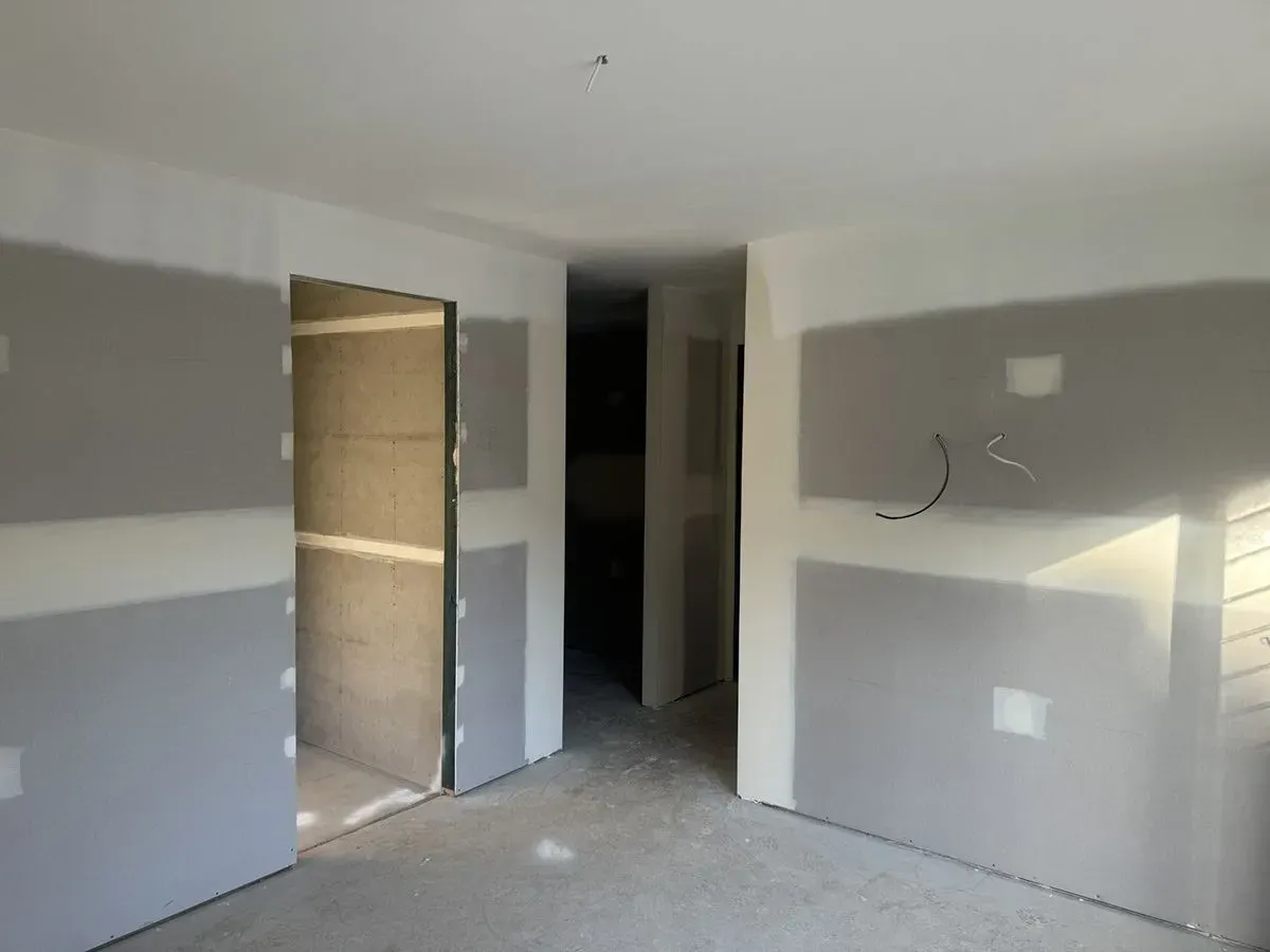 Person Using a Trowel to Apply Drywall Mud to A White Wall — Completely Plastered North Coast in Kyogle, NSW