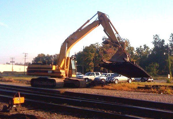 An excavator moves track panel for installation