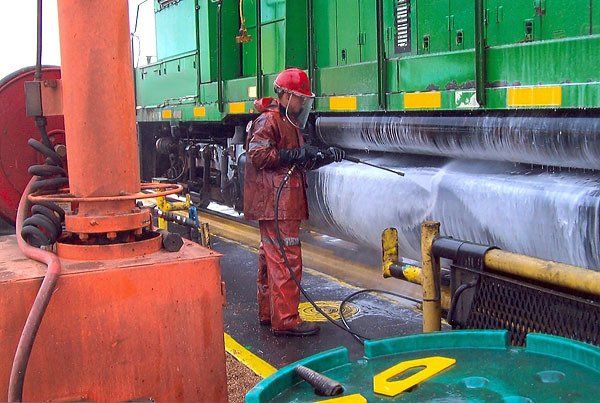 Hulcher crew member pressure washes the undercarriage of an engine