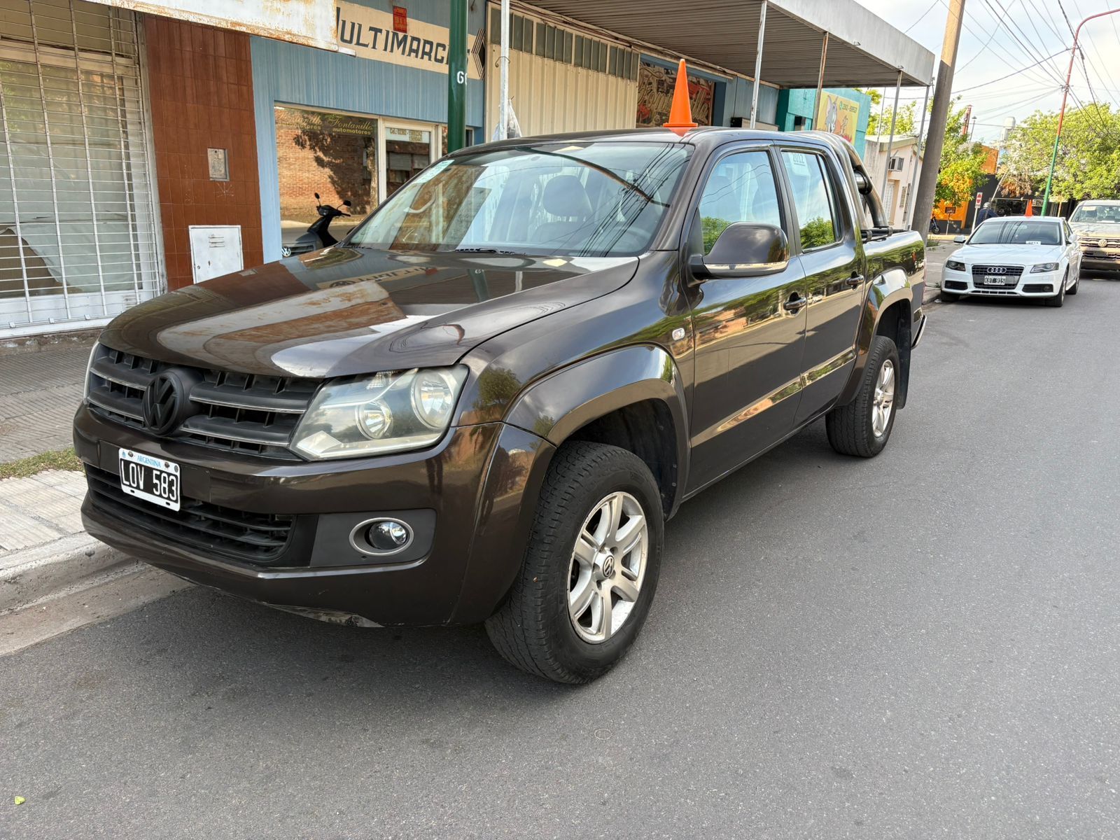 Camioneta Volkswagen Amarok color marrón estacionada en una calle frente a un edificio.