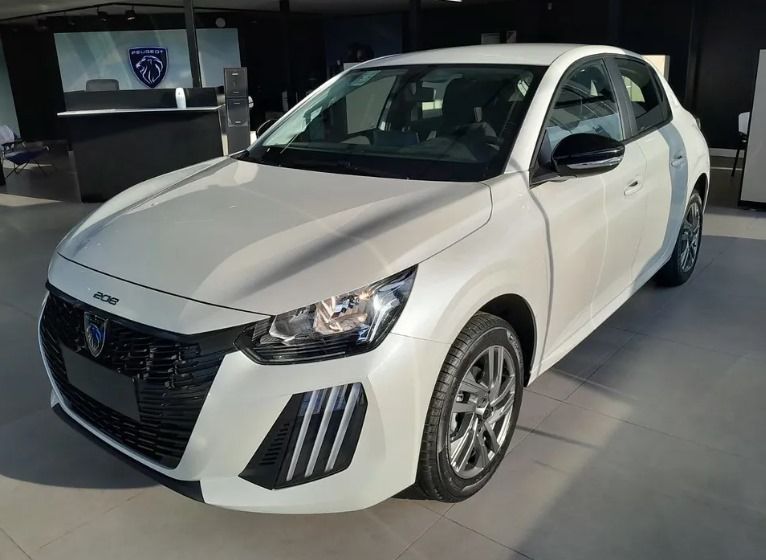 Peugeot 208 blanco aparcado en el interior, cerca de un mostrador de recepción.