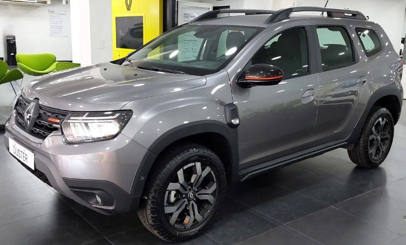 SUV Renault Duster color gris, estacionado en el interior con detalles en negro, portaequipaje y ruedas oscuras.