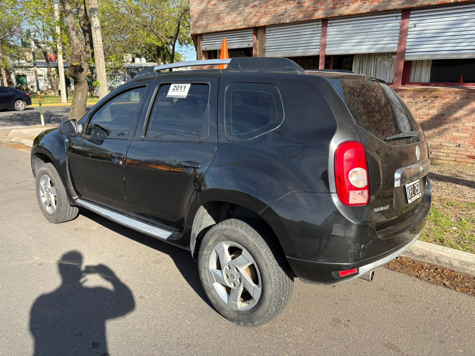 Una camioneta negra estacionada en la calle. Se ve la sombra de una persona tomando una foto.