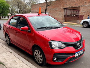 Un sedán Toyota rojo estacionado en una calle con un cono naranja en el techo.