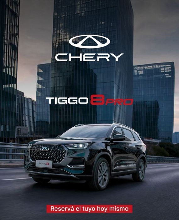 SUV Chery Tiggo 8 Pro en una calle de la ciudad, con el logotipo de Chery sobre un rascacielos. 