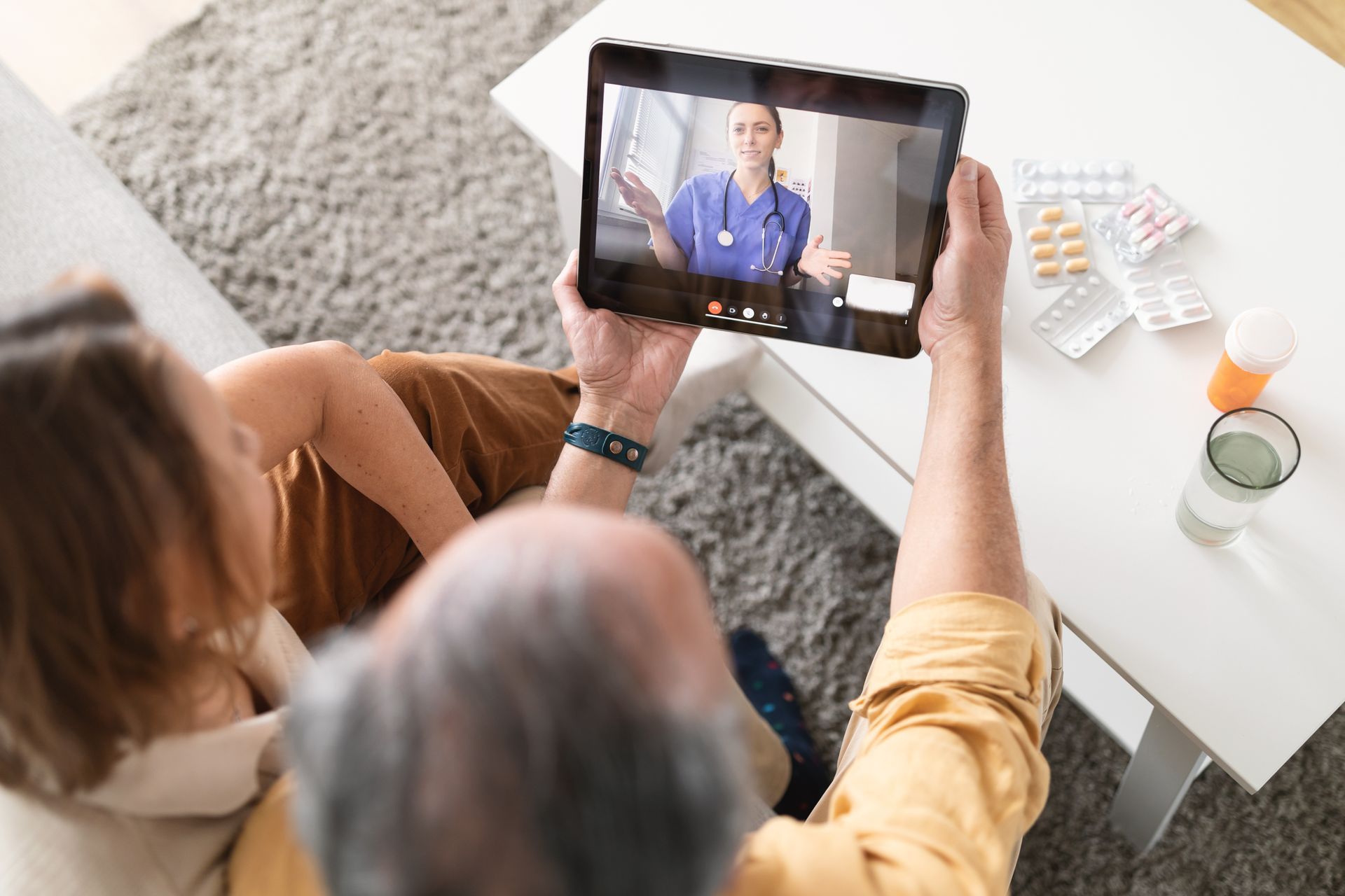 elderly couple on a video call with a healthcare provider using their tablet at home