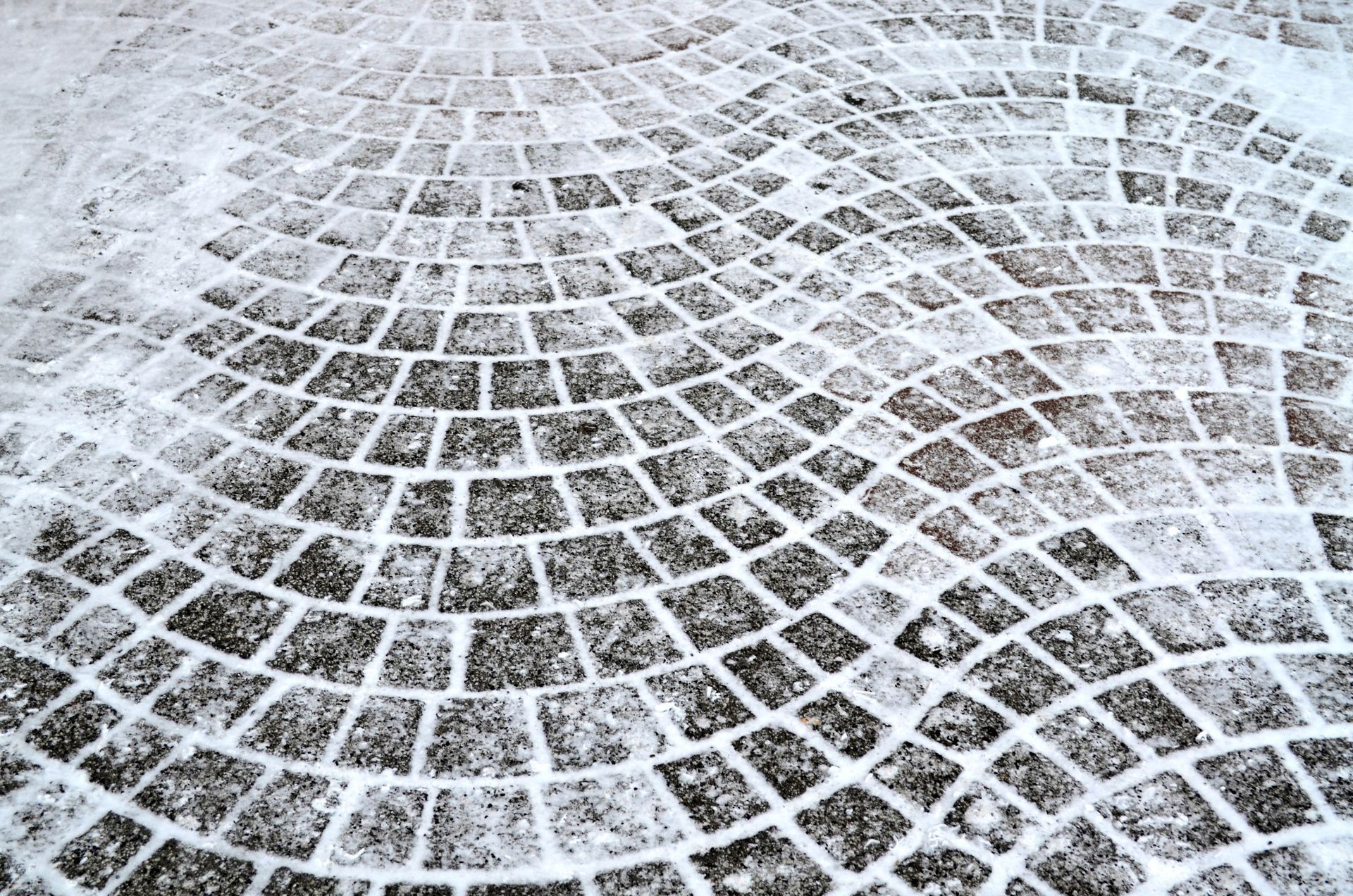 Snow-covered brick pathway in a curved pattern.