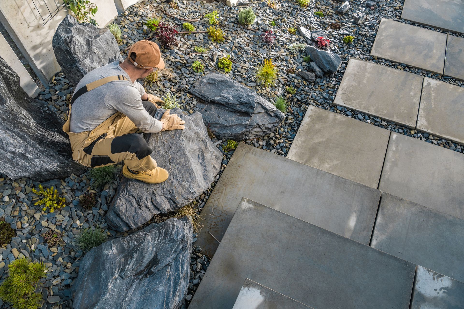 A man is kneeling on a rock in a garden.