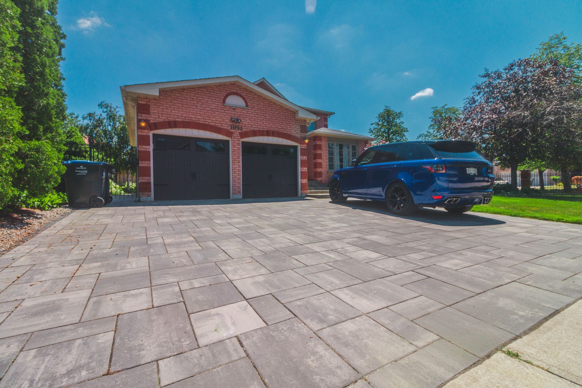 A blue car is parked in a driveway in front of a house.