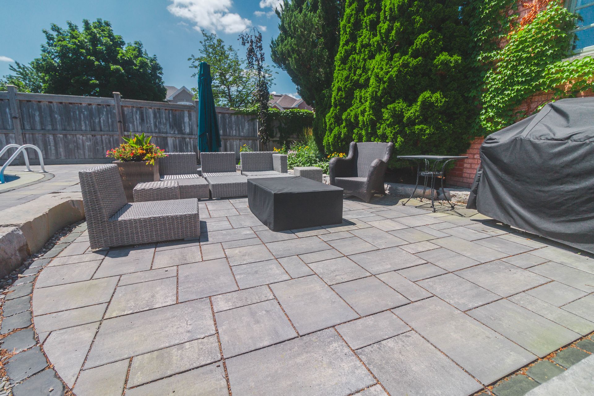 A patio with a grill , chairs , table and umbrella.