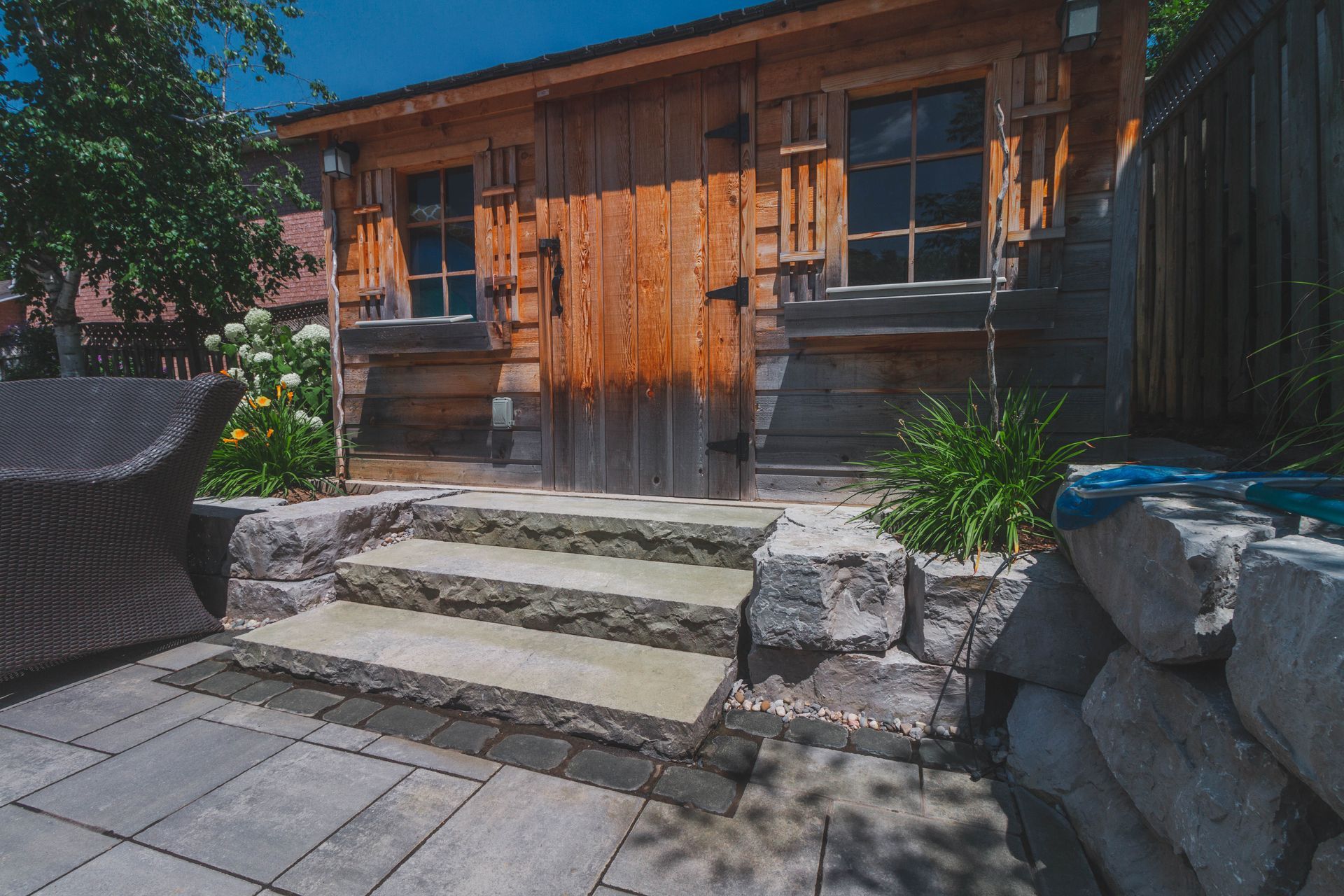 There are stairs leading up to a wooden building in the backyard.