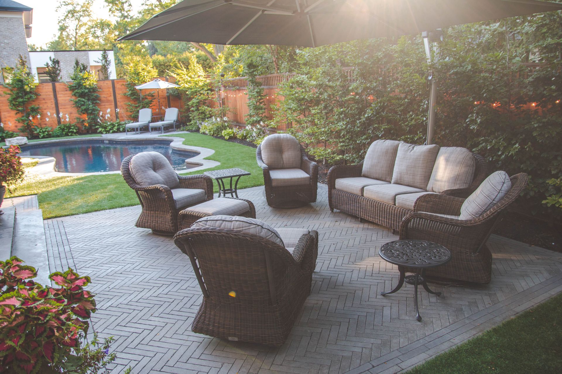 A patio with furniture and an umbrella in front of a pool