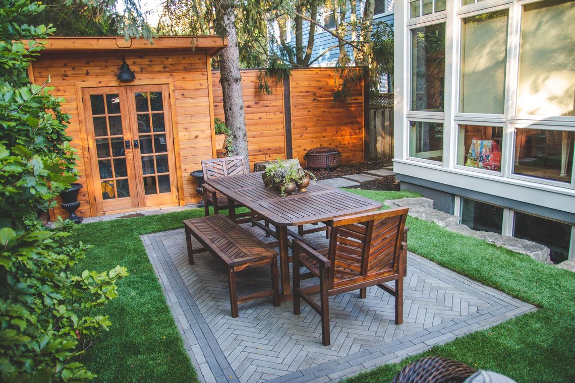 There is a table and chairs in the backyard of a house.