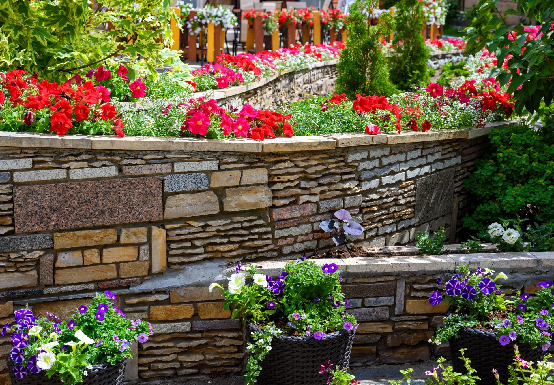 A stone wall surrounded by potted plants and flowers.