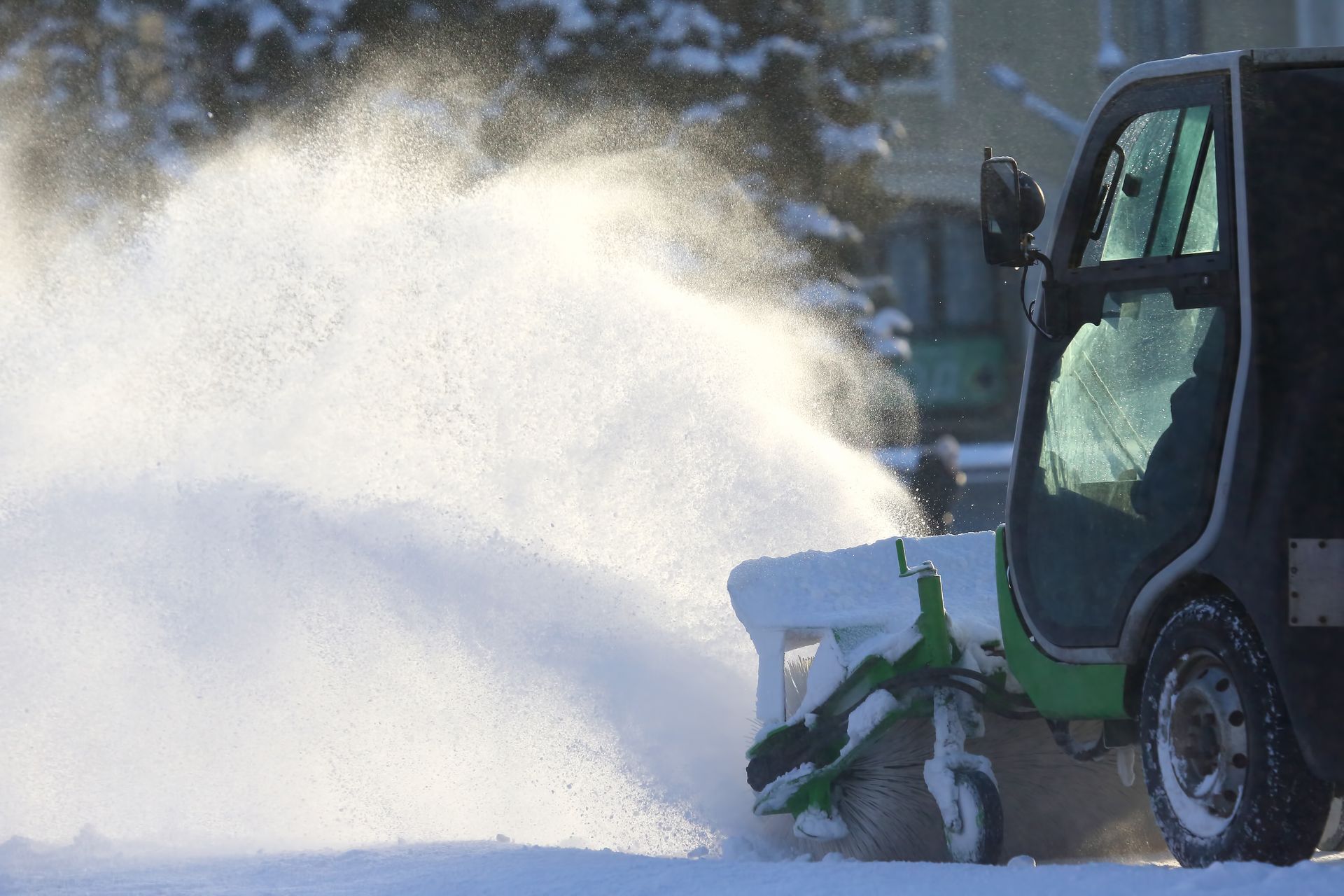 A snow blower is blowing snow from the ground.