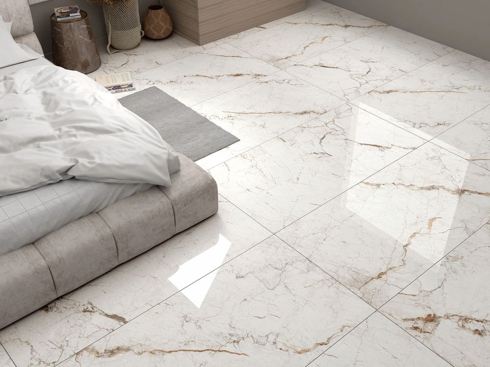 Suelo de baldosas gris claro junto a una cama baja gris y almohadas con vetas geométricas que imitan el mármol.