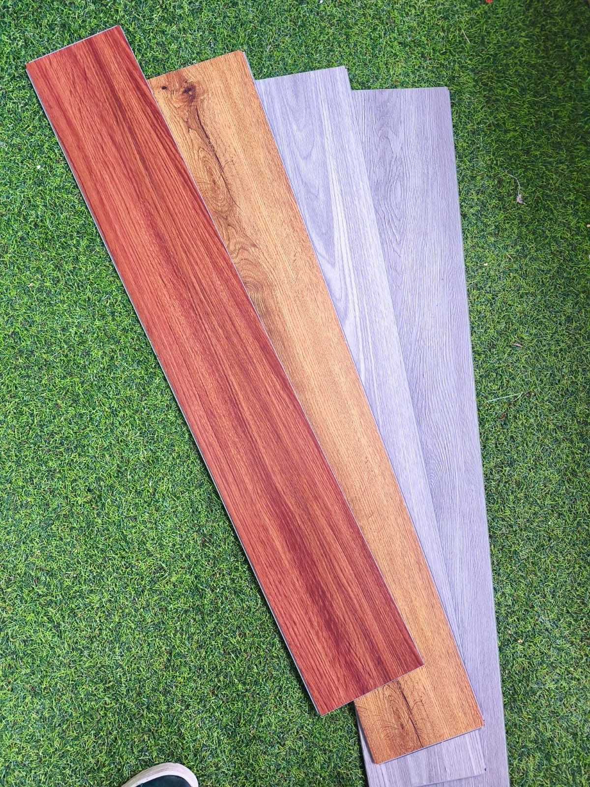 Cuatro listones de madera de color rojo, tostado y morado pálido dispuestos sobre hierba verde.