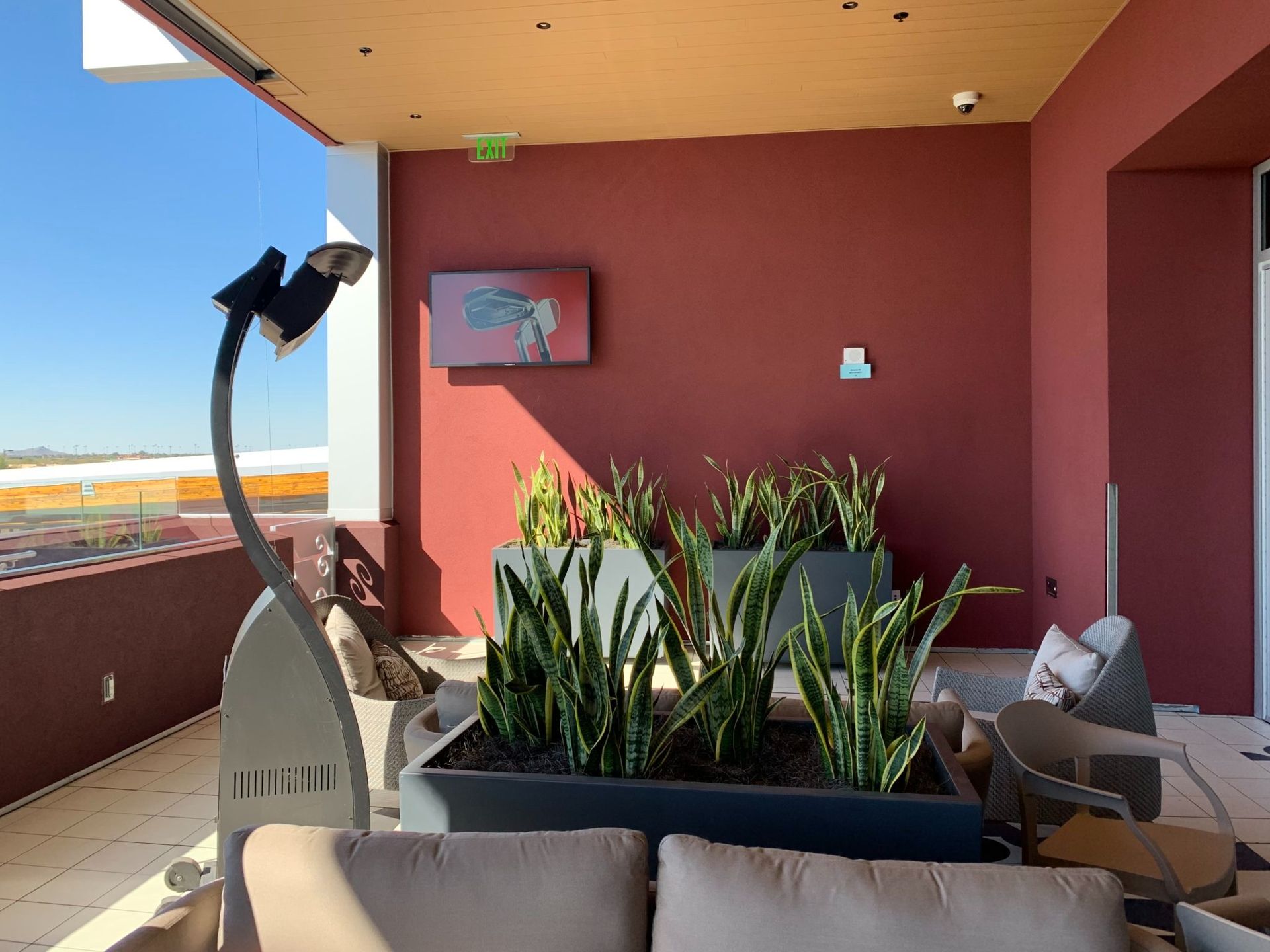 Outdoor seating area with potted plants, a patio heater, and a red wall.