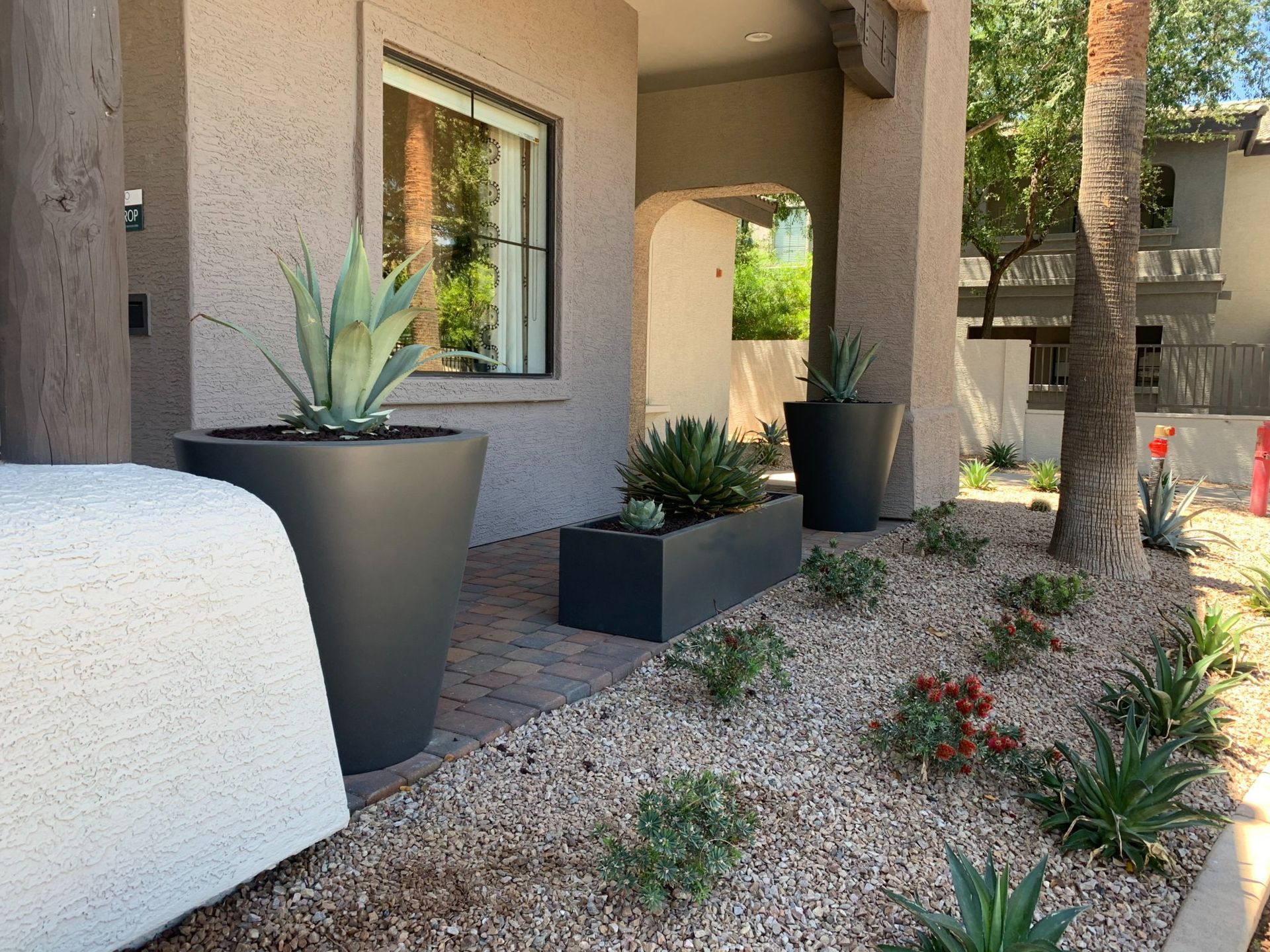 Exterior of house with gray planters and landscaping with gravel and various plants.