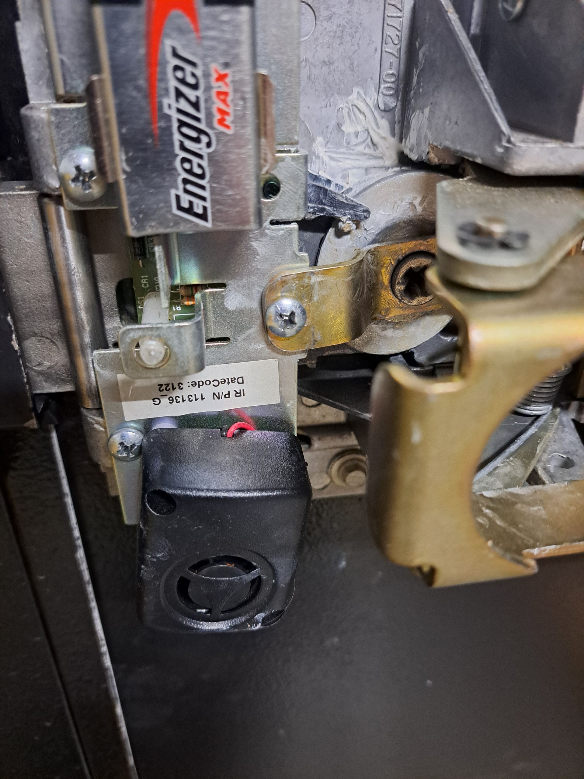 Close-up of a safe's internal components, including an Energizer battery, a small black speaker, and metal locking mechanisms.