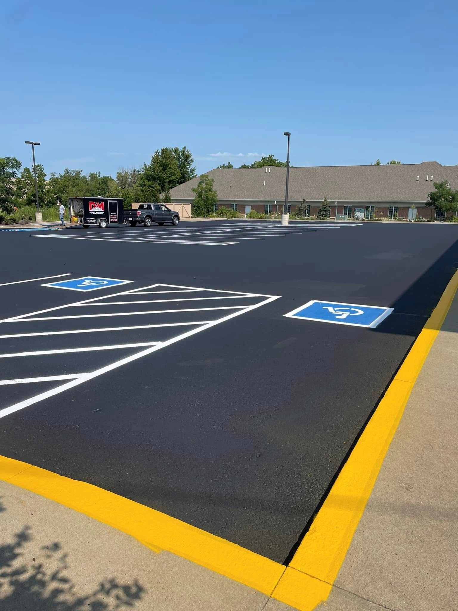Newly paved parking lot with handicap parking spaces marked in white and blue, yellow curb. Newly paved parking lot with handicap parking spaces marked in white and blue, yellow curb.