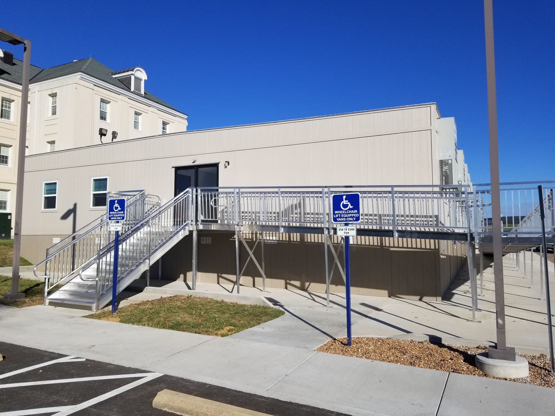 Exterior building with accessible ramp and stair access, two blue handicap parking signs.