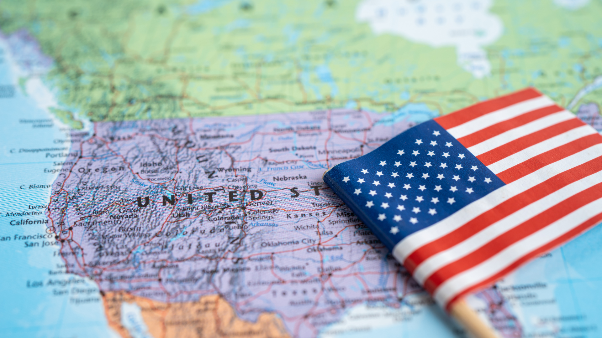 A small american flag is sitting on top of a map of the united states.