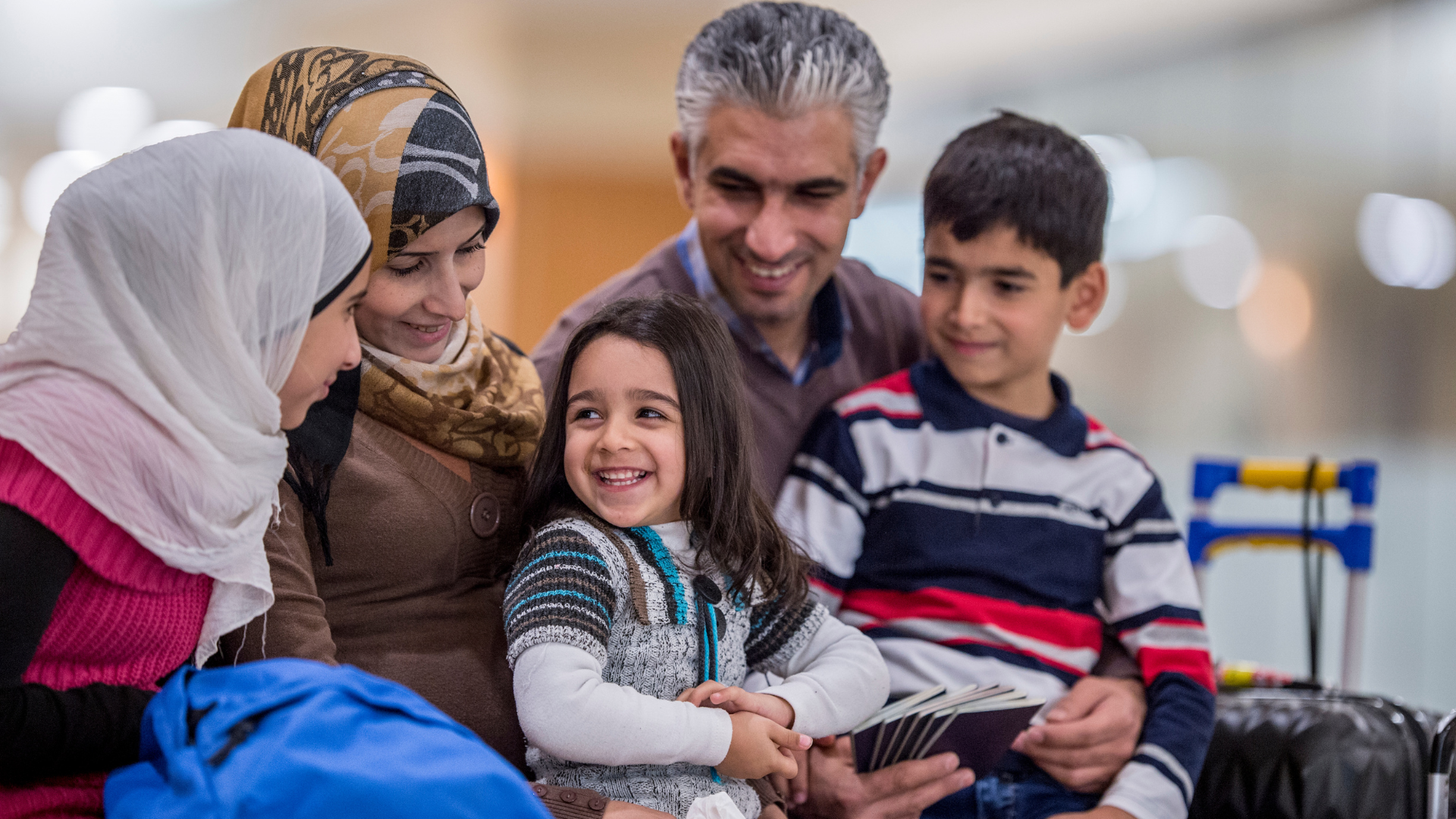 A group of people are sitting around a table with luggage.