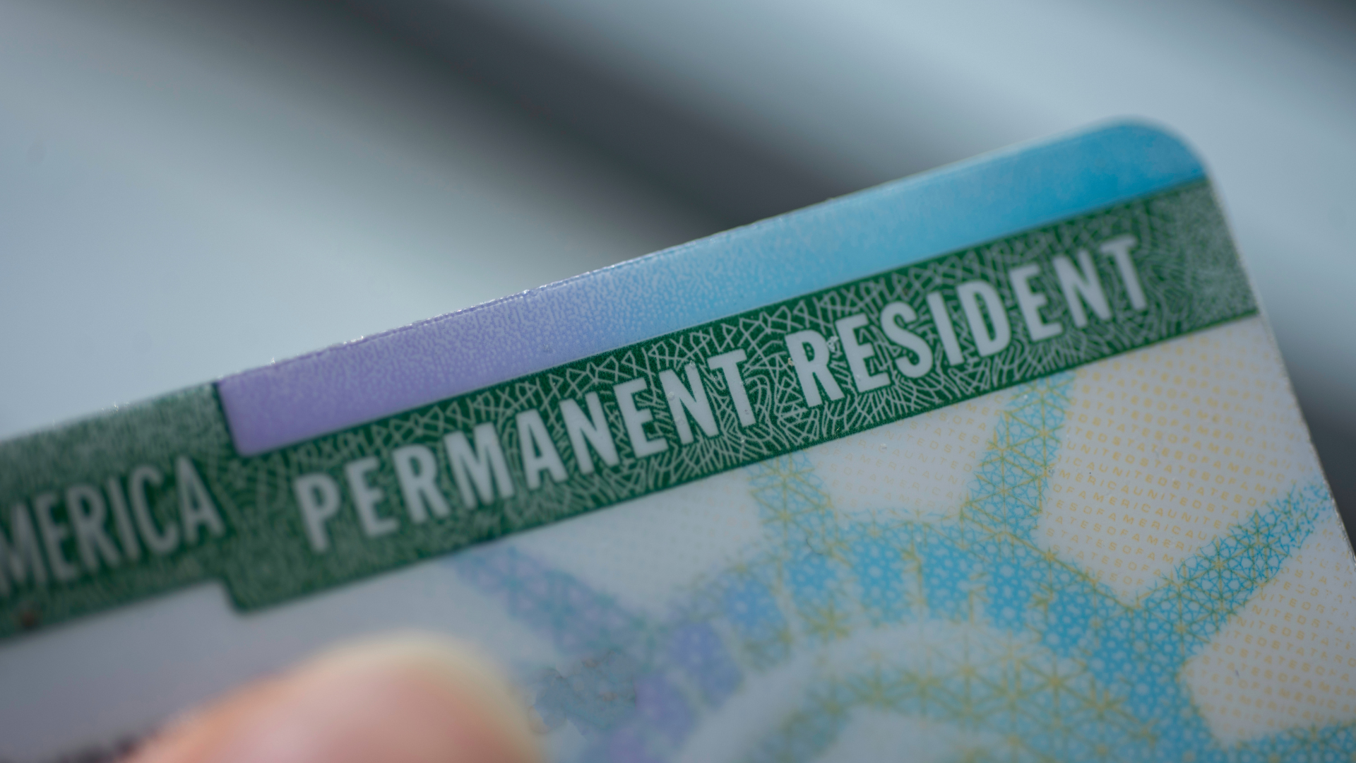 A person is holding a permanent resident card in their hand.