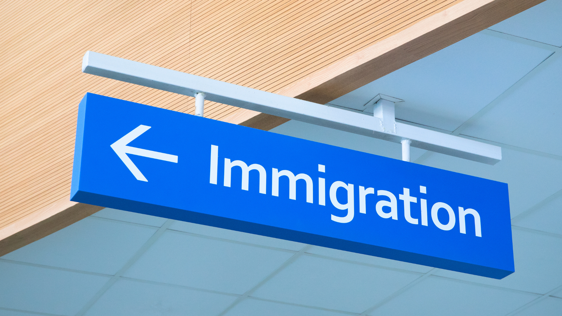 A blue sign that says immigration is hanging from the ceiling.