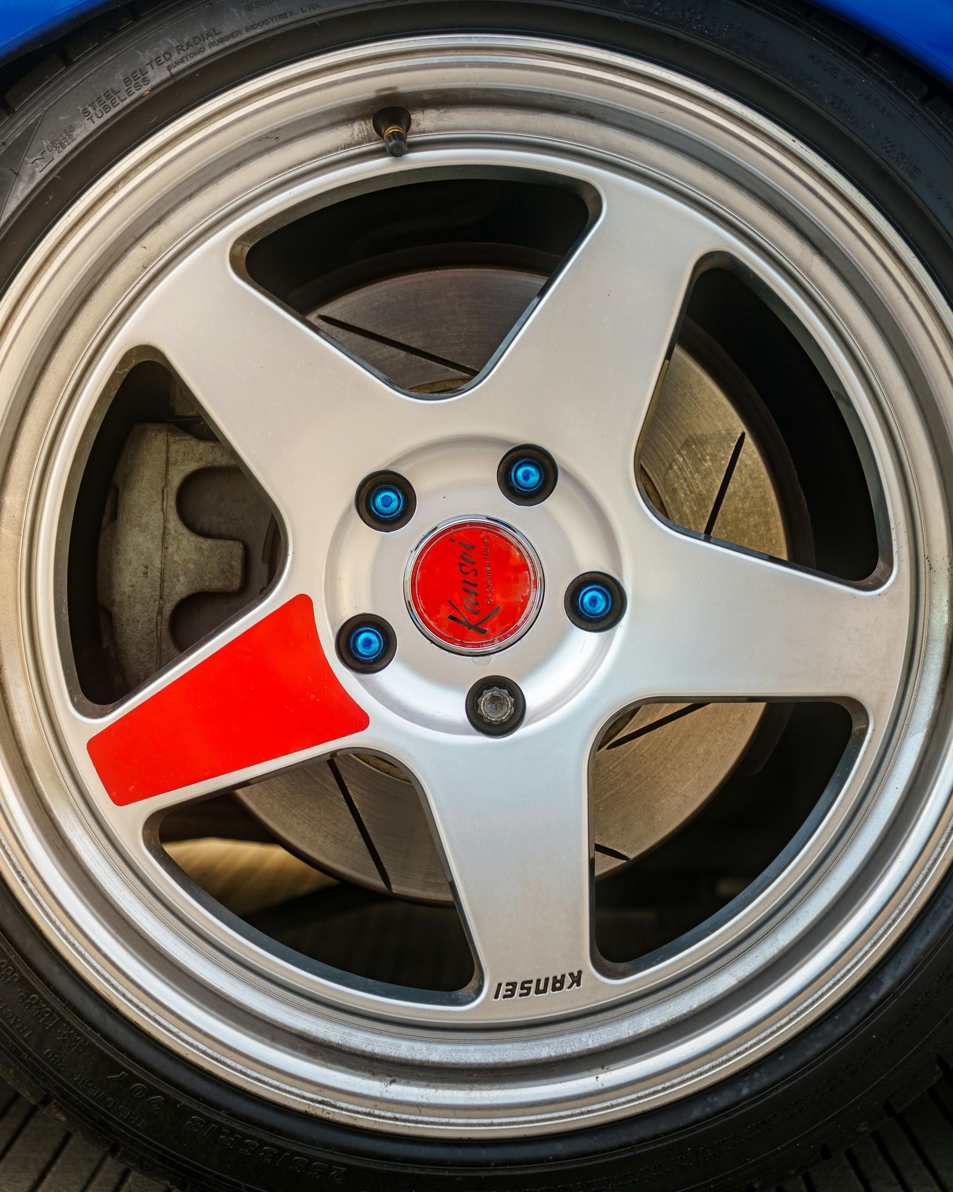 Close-up of a silver five-spoke car wheel with red accents and a red center cap