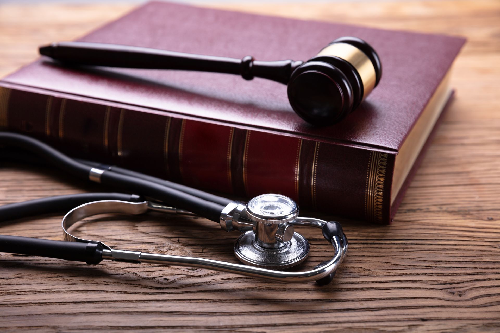 A stethoscope is sitting on top of a book next to a judge 's gavel.