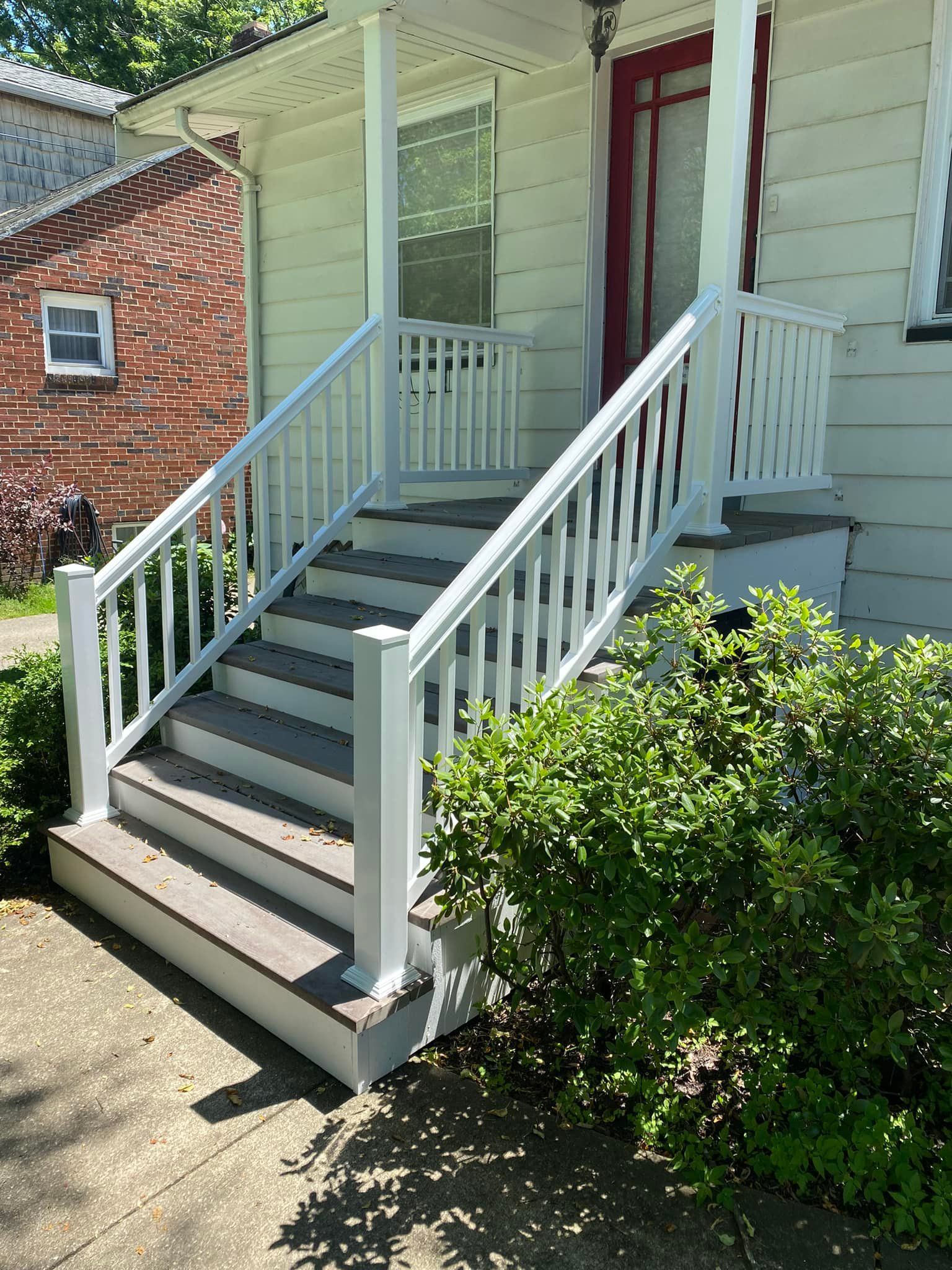 A white house with a porch and stairs with a white railing.