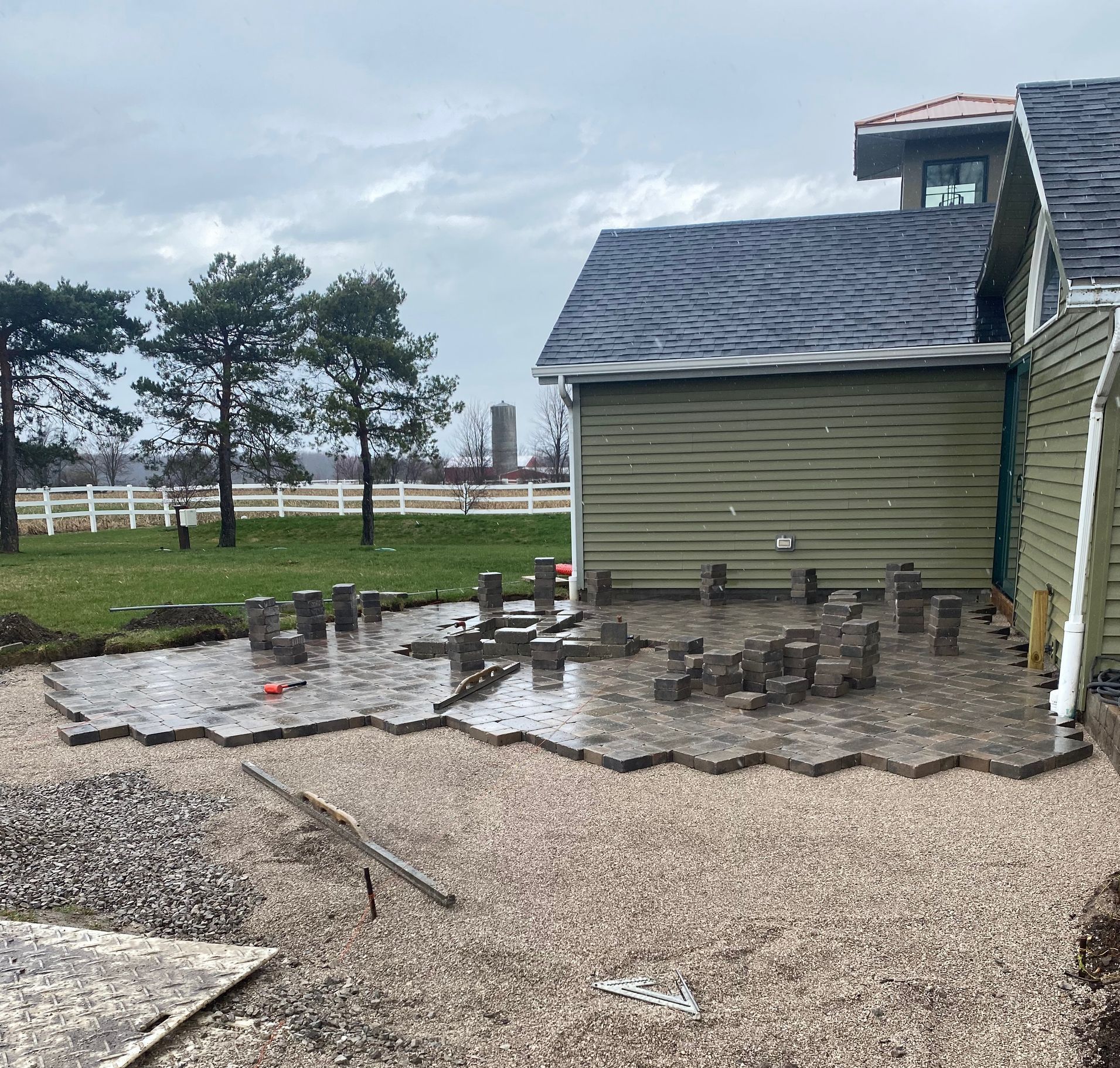 A man is sitting on a bench in a garden in front of a house.