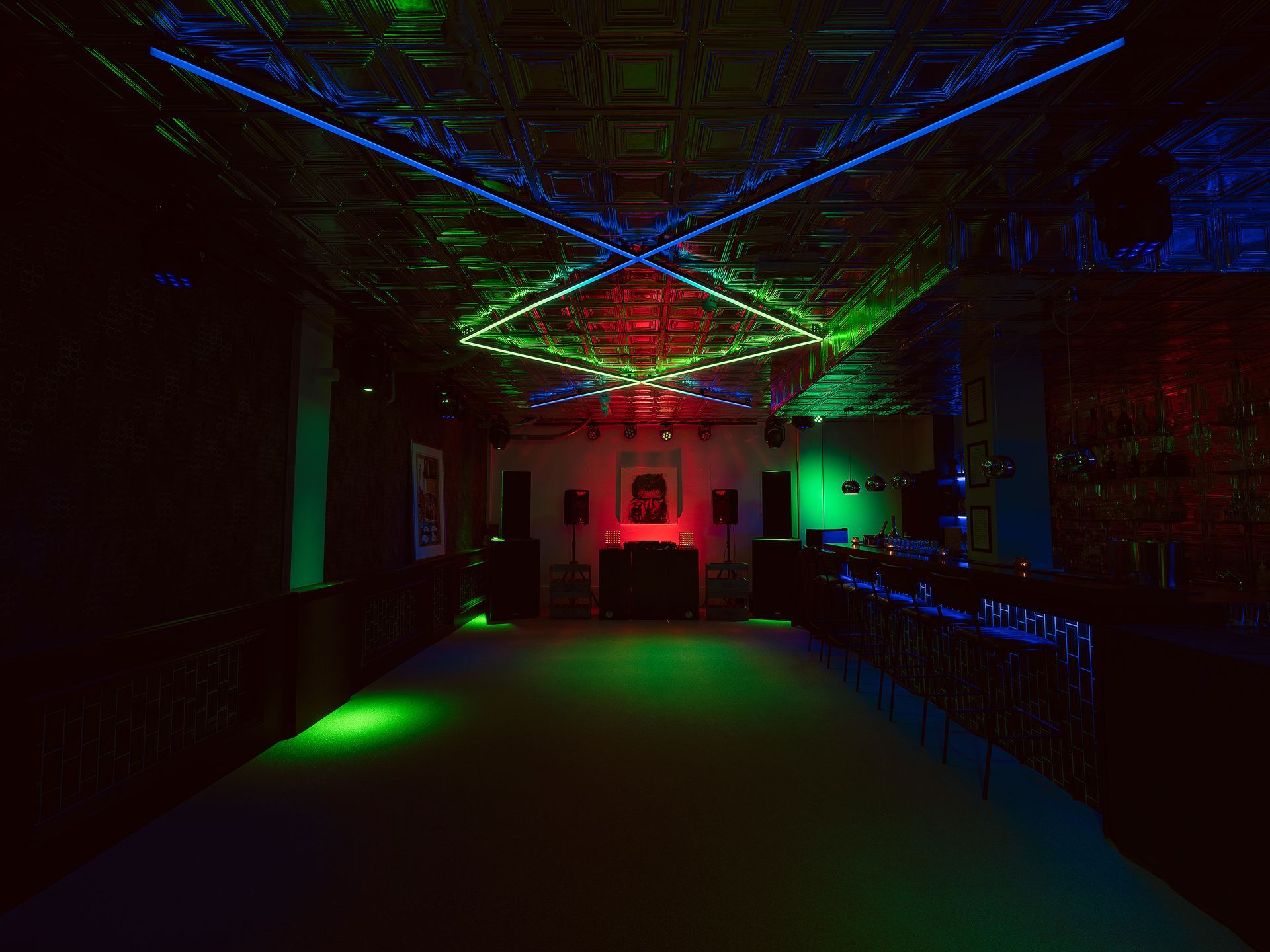 Dark club interior with colorful LED light display on the ceiling above a central dance floor.
