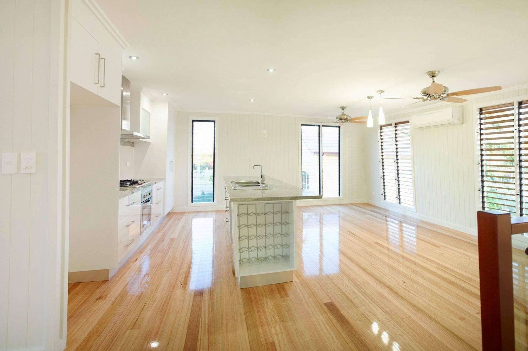 A Living Room With Hardwood Floors, a Kitchen, and a Ceiling Fan — Pro-Jax Pty Ltd in Bohle, QLD